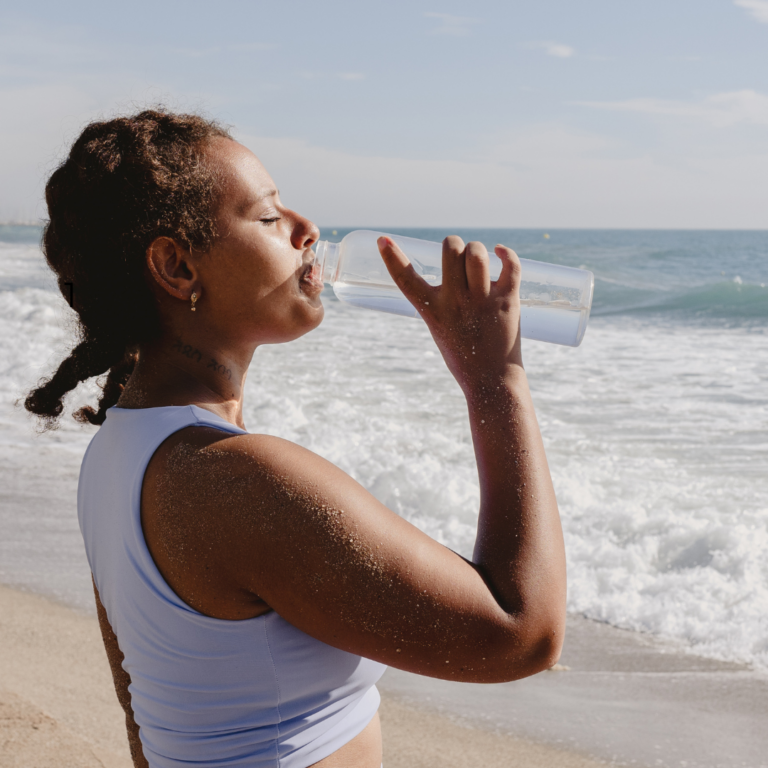 woman drinking water on beach